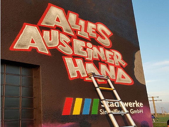 Schaltanlage zwischen Darmsheim und Ehningen An einer Hauswand stehen die Worte "Alles aus einer Hand" und das Logo der Stadtwerke Sindelfingen. Eine Leiter lehnt an der Hauswand.