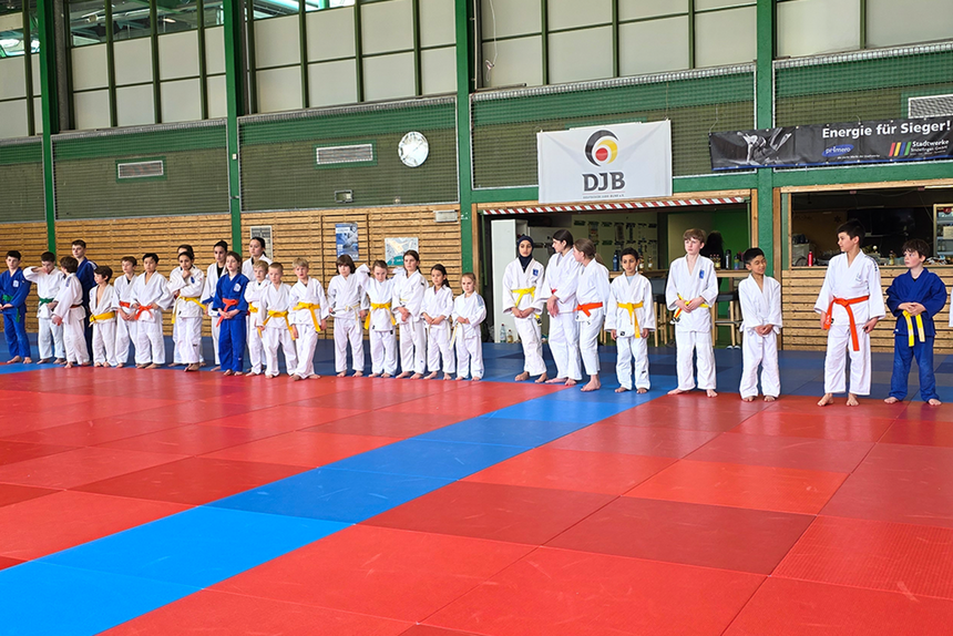 Die Kinder der Judo-Abteilung stehen in einer Reihe auf der Judomatte in der Sporthalle