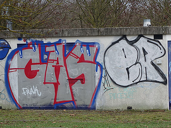 Ein kleines technisches Gebäude ist unschön mit Graffitis beschmiert.
