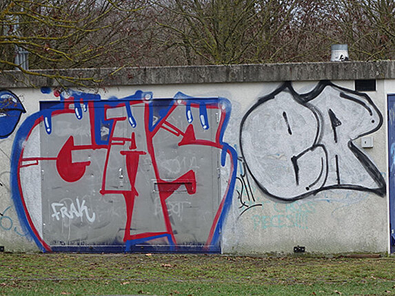 Ein kleines technisches Gebäude ist unschön mit Graffitis beschmiert.