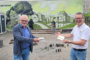 Herr Dr. Hoffmann und Kulturamtsleiter Markus Nau stehen vor dem fertigen Graffiti-Kunstwerk. Das Motiv: Eine Stadtsilhouette in Grüntonen, die einzelnen Gebäude formen das Wort "Sindelfingen".