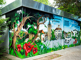 Ein technisches Gebäude mit einem grossflächigen Graffiti. Das Motiv: Der Marktplatz von Sindelfingen, umrahmt von grossen Bäumen und Blumen.