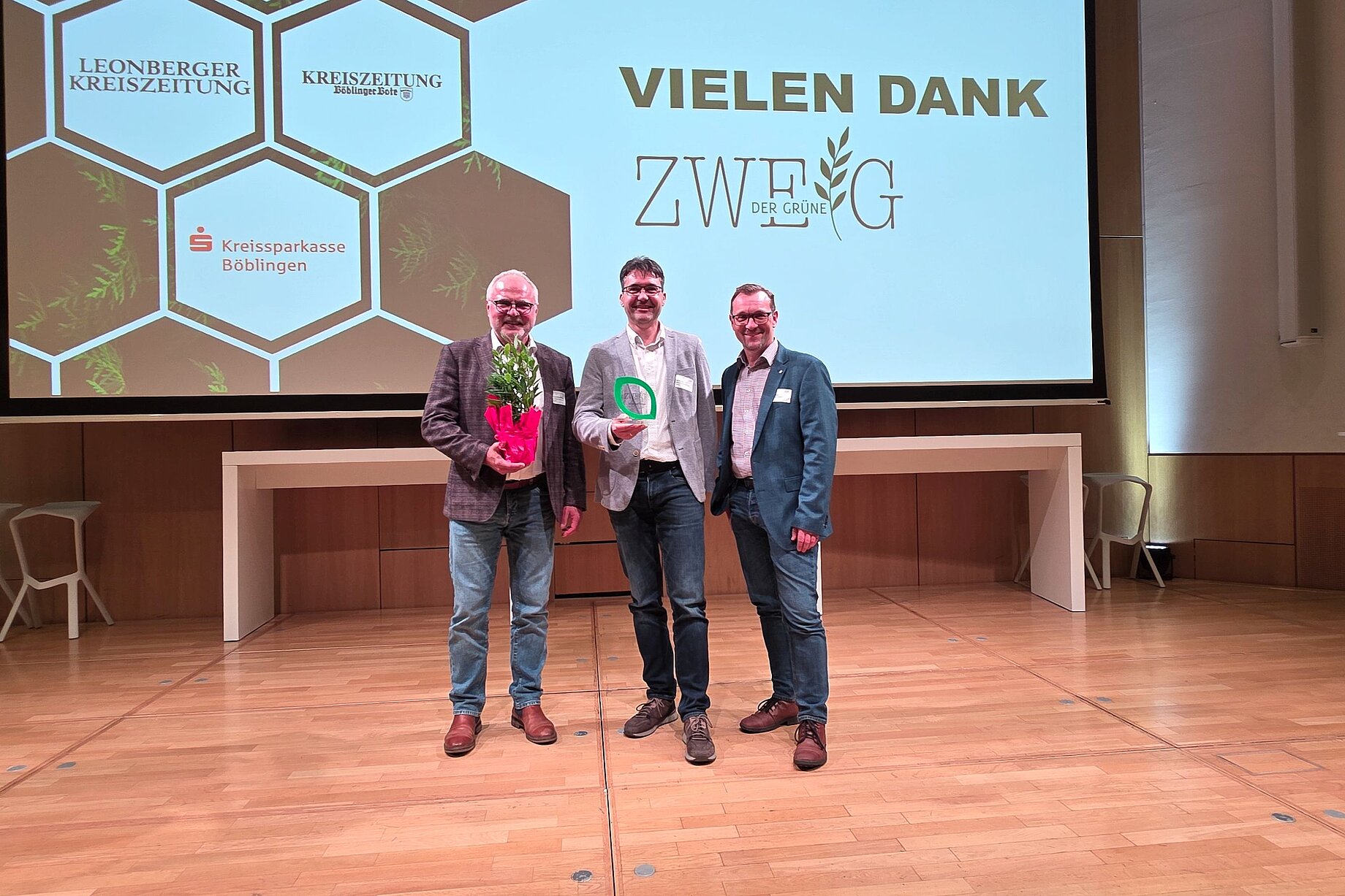 Die Geschäftsleitung der Stadtwerke Sindelfingen hat den Preis Der grüne Zweig gewonnen und steht auf der Bühne