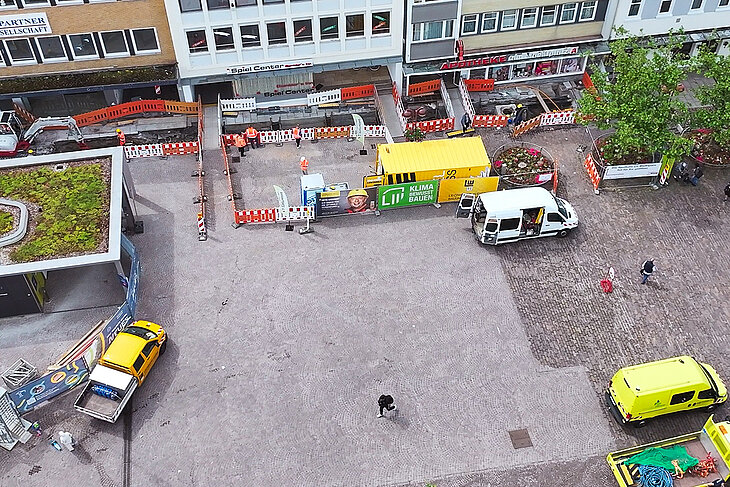 Baustelle auf dem Marktplatz. Es stehen Baustellenfahrzeuge und Transporter um die aufgegrabene Baustelle