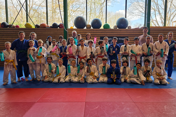 Die Trainer und Kinder Judoabteilung sowie Vertreter der Stadtwerke Sindelfingen stehen alle auf einer Judo-Matte und halten die gesponsorten Getränkeflaschen in die Luft