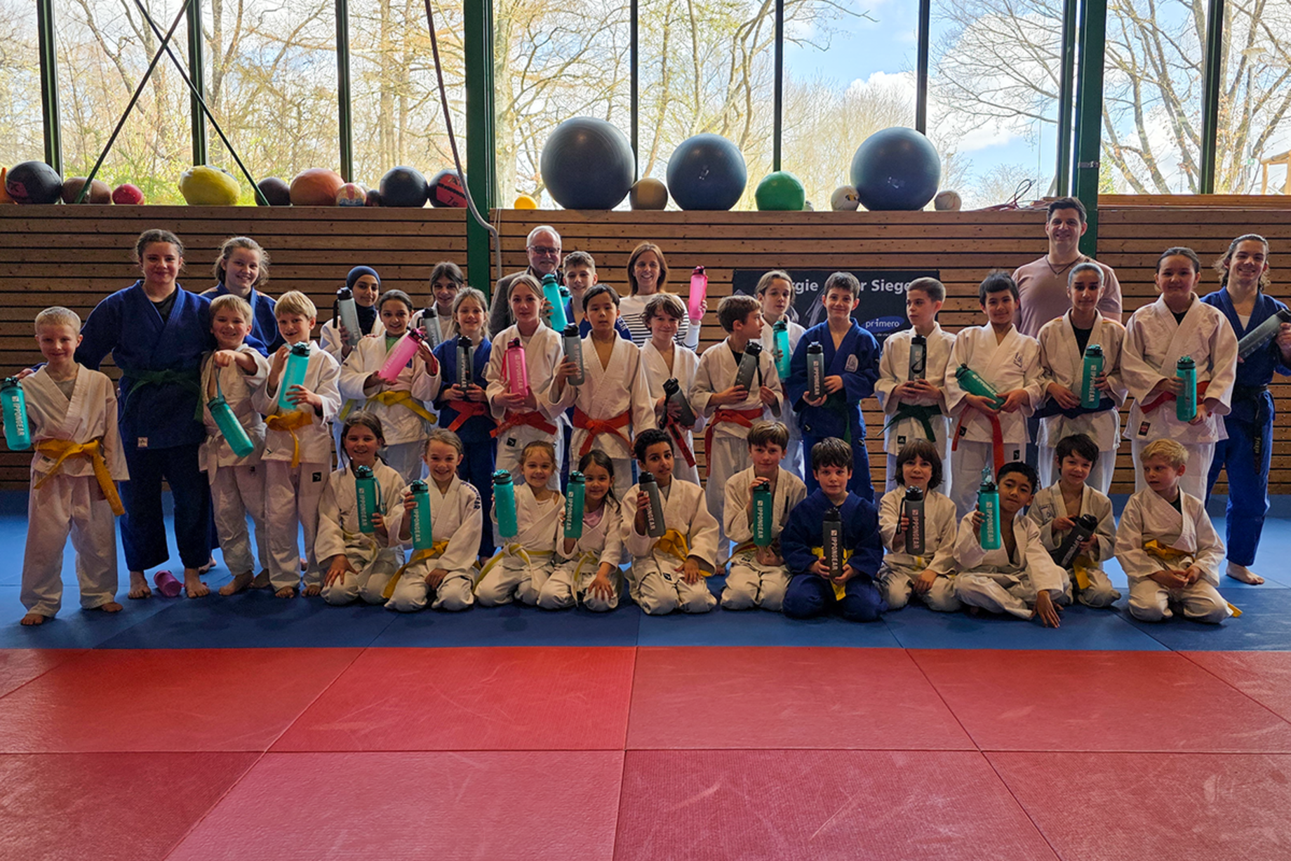 Die Trainer und Kinder Judoabteilung sowie Vertreter der Stadtwerke Sindelfingen stehen alle auf einer Judo-Matte und halten die gesponsorten Getränkeflaschen in die Luft