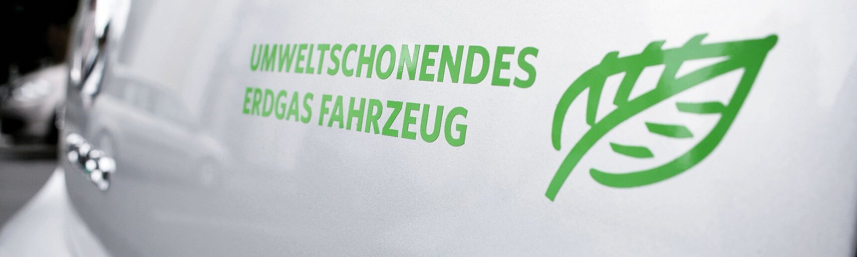 Nahaufnahme eines Autoaufklebers. "Umweltschonendes Erdgas Fahrzeug", daneben ein grünes Blatt.