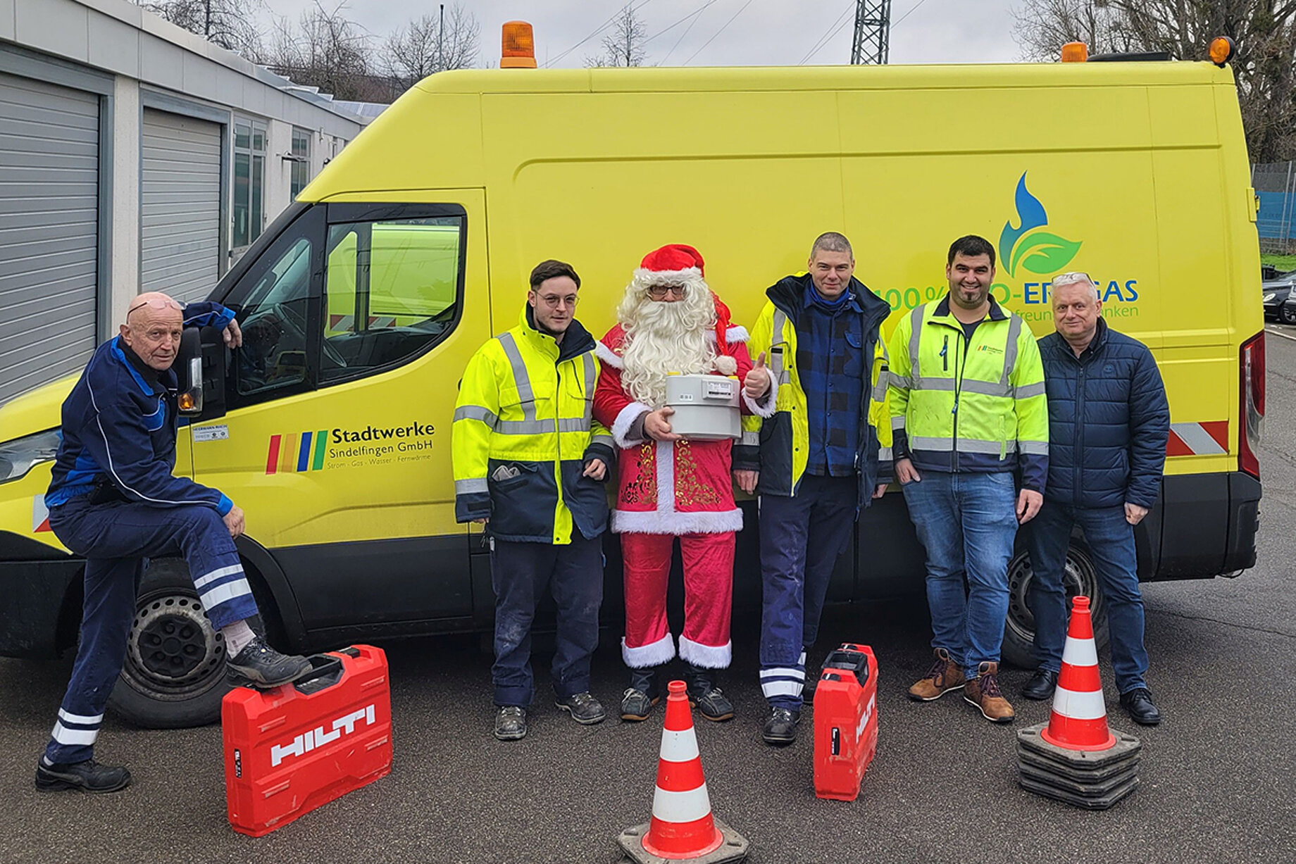 Die Mitarbeiter des Bereitschaftsdienstes posieren vor einem Transporter der Stadtwerke. Zwischen ihnen steht ein Weihnachtsmann.
