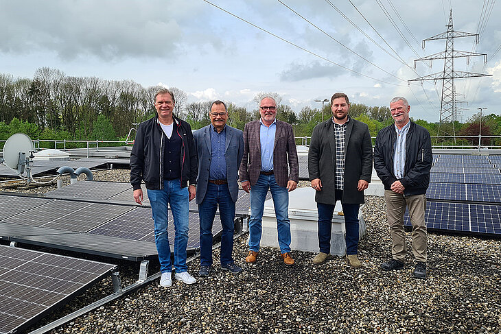 Pressefoto: Herr Dr. Hoffmann und vier weitere Männer stehen auf dem Dach eines Gebäudes mit einer Fotovoltaikanlage.