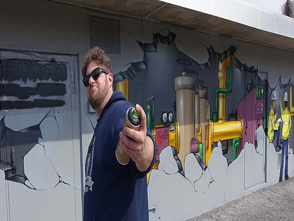 Gasdruckregelstation in der Rudolf-Harbig-Straße Der Graffiti-Künstler hält eine Sprühdose in der Hand und posiert vor seinem Werk.