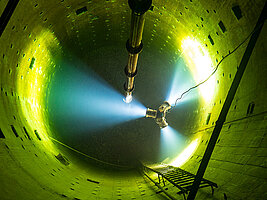 Blick in den Tiefenbrunnen Floschen  Blick von oben in einen leeren, sanierungsbedürftigen Wassertank. Mit Baustrahlern ist dieser ausgeleuchtet, eine Leiter ist an der Wand befestigt.