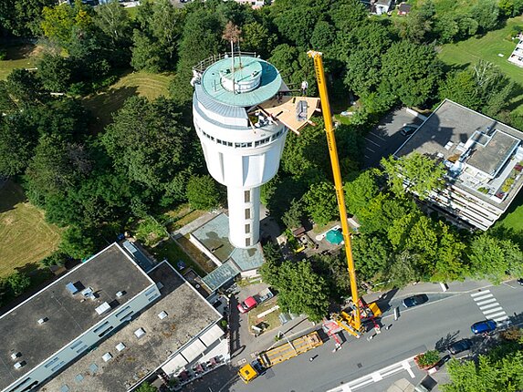 Luftaufnahme der Sanierung am Wasserturm Goldberg. Ein riesigerKran befördert Baumaterial gan nach oben.