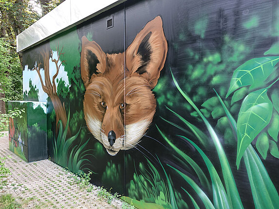 Ein technisches Gebäude mit einem grossflächigen Graffiti. Das Motiv: Ein riesiger Fuchskopf ragt aus dem Dickicht hervor.