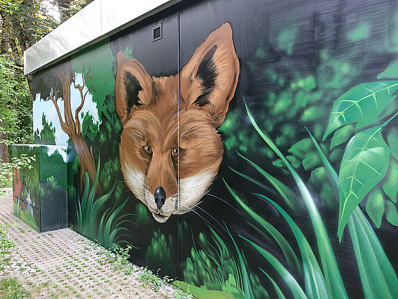 Ein technisches Gebäude mit einem grossflächigen Graffiti. Das Motiv: Ein riesiger Fuchskopf ragt aus dem Dickicht hervor.