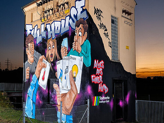 Das technische Gebäude in Darmsheim mit einem großflächigen Graffiti. Das Motiv: Eine Pokerrunde und auf den Spielkarten sind Symbole für Wärme, Gas, Wasser und Strom, darüber stehen die Worte "Full House".  