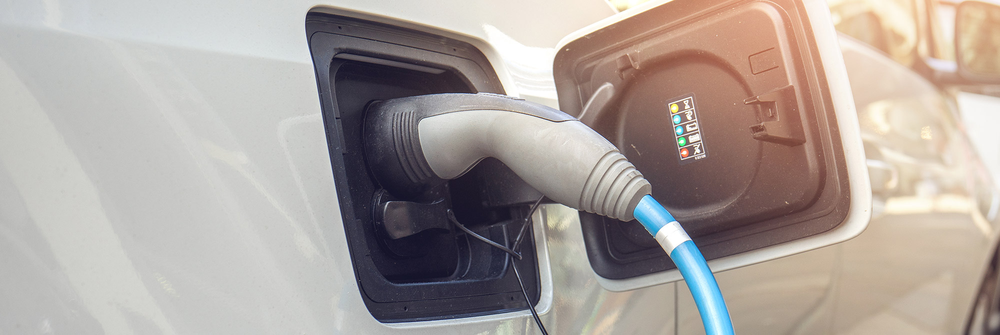 Nahaufnahme eines Ladesteckers, welcher gerade in einem Elektroauto steckt.