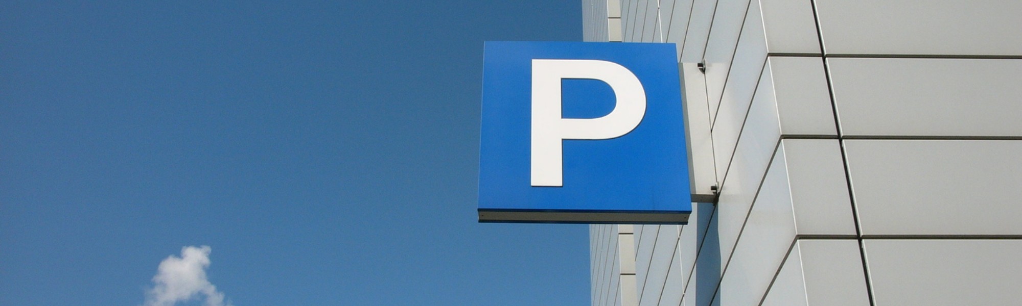 Das typische Parkplatz Symbol an einer Hauswand vor einem blauen Himmel.